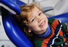 Próchnica – najdroższa w leczeniu choroba przewlekła na świecie dziecko na fotelu dentysty, uśmiecha się szeroko