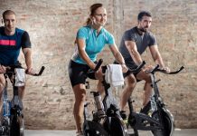 Medicover po przejęciu CityFit ma ponad 170 własnych obiektów sportowych kobieta i dwóch mężczyzn ćwiczą na rowerach w klubie fitness