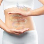 Zapalne choroby jelit zmieniają życie kobieca sylwetka, jedna ręka z góry a druga z dołu brzucha na którym narysowane są jelita