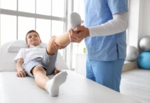 Rehabilitacja onkologiczna dzieci i młodzieży – jakie sposoby sprawdzają się w pracy z małymi dziećmi, a jakie z nastolatkami? dziecko ćwiczy przy pomocy rehabilitanta