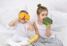 Zdrowie najmłodszych zaczyna się na talerzu radosne dzieci trzymają owoce i warzywa. dziewczynka brokuł, chłopiec pomarańczę