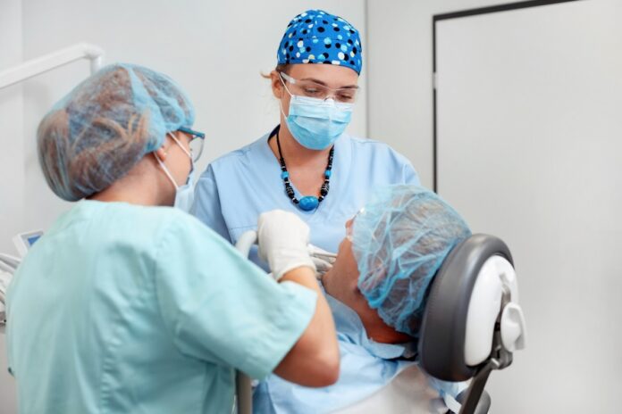 dentystka wraz z asystentką sprawdzają jamę ustną pacjenta