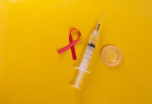 Zakażenia HIV dotyczą także seniorów prezerwatywa lateksowa czerwona wstazka i strzykawka na żółtym tle. zdjęcie ilustracyjne do HIV/AIDS