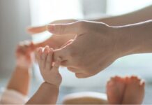 Potrzebny jest koordynator onkopłodności widać rączki i nóżki małego dziecka oraz ręce dorosłego. dorosły podaje swoje ręce dziecku