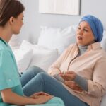 Pacjentki z rakiem piersi chcą mieć realny wpływ na sposób leczenia pacjentka z chustą na głowie siedzi na łóżku szpitalnym i rozmawia z lekarką