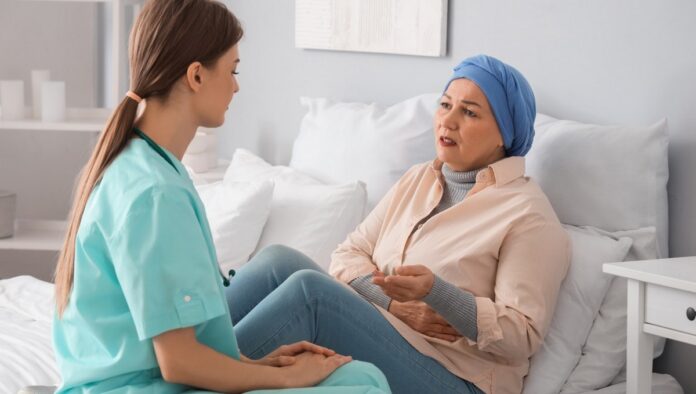 pacjentka onko na łóżku szpitalnym rozmowa z lekarzem.jpeg pacjentka z chustą na głowie siedzi na łóżku szpitalnym i rozmawia z lekarką