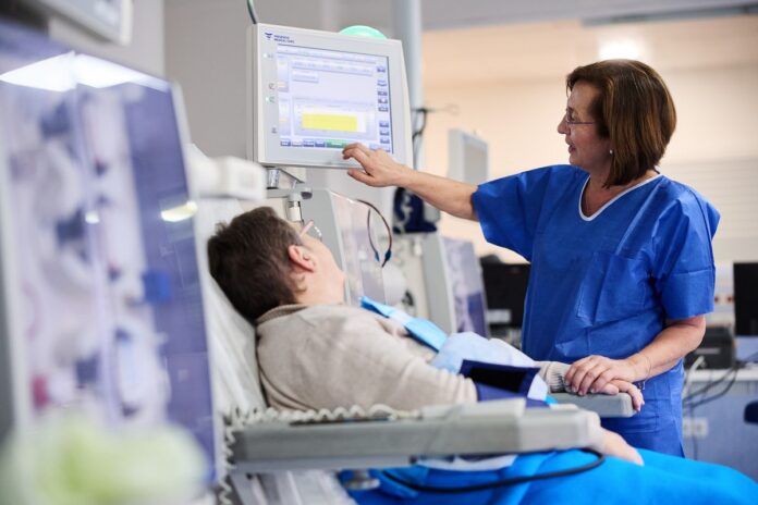 stacja dializ - pacjent siedzi na fotelu a pielęgniarka ustawia sprzęt