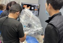 Roboty dentystyczne wkraczają do gabinetów robot dentystyczny podczas pracy. wokół stoją lekarze i obserwują jego pracę