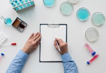 Urteste przetestuje test Panuri w trzech krajach na białym blacie stoją próbówki, szkła laboratoryjne oraz widać ręce mężczyzny zapisującego wyniki na kartce