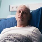 Medialny obraz raka jest zniekształcony młody mężczyzna leży na łóżku szpitalnym. ma smutną minę